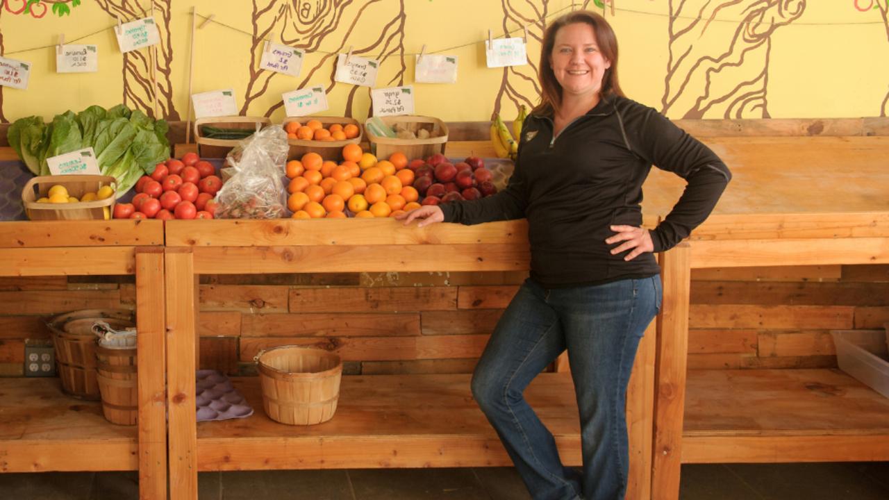 Dr. Jennifer Lucarelli posing for a photo in front of a fruit stand.